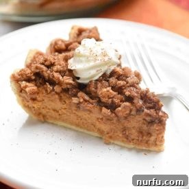 Pumpkin Praline Pie topped with whipped cream sitting on a round white plate
