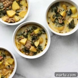 4 white bowls of Zuppa Toscana soup garnished with herbs