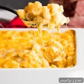 Baked Macaroni and Cheese in a square white casserole dish being spooned out