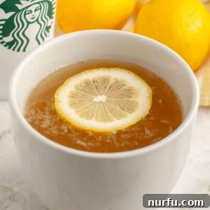 Starbucks Soothing Elixir 6 A steaming mug of warm Medicine Ball Tea, garnished with a fresh lemon slice and a mint sprig, ready to be enjoyed.