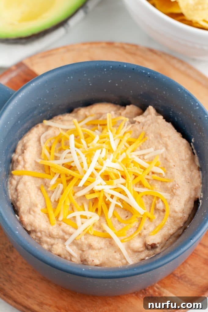 Upgrade Canned Refried Beans for Authentic Restaurant Flavor 2 Bowl of refried beans topped with cheese, ready to be served as a restaurant-quality side dish or dip.