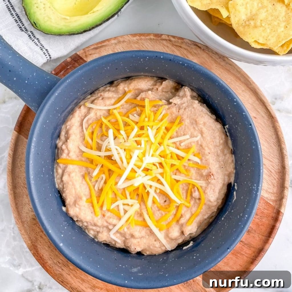 Upgrade Canned Refried Beans for Authentic Restaurant Flavor 5 Bowl of beans topped with cheese, showcasing the finished restaurant-quality refried beans.