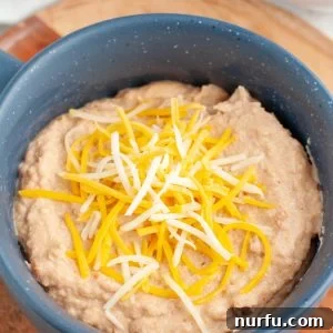 Upgrade Canned Refried Beans for Authentic Restaurant Flavor 6 Bowl of refried beans topped with cheese.