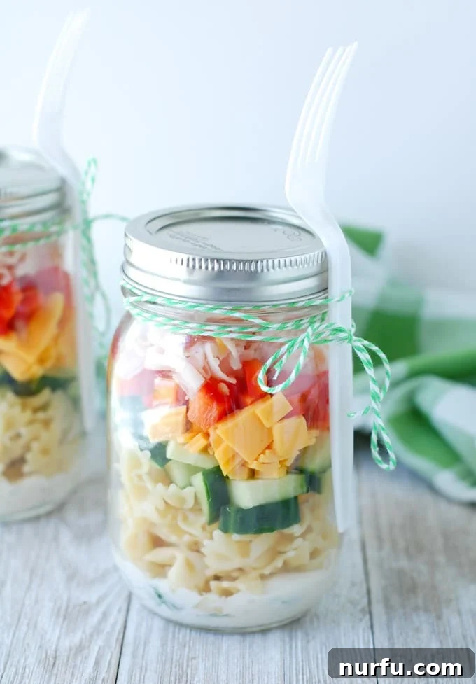 Vibrant pasta salad layered in a clear mason jar, ready for a healthy, portable lunch.