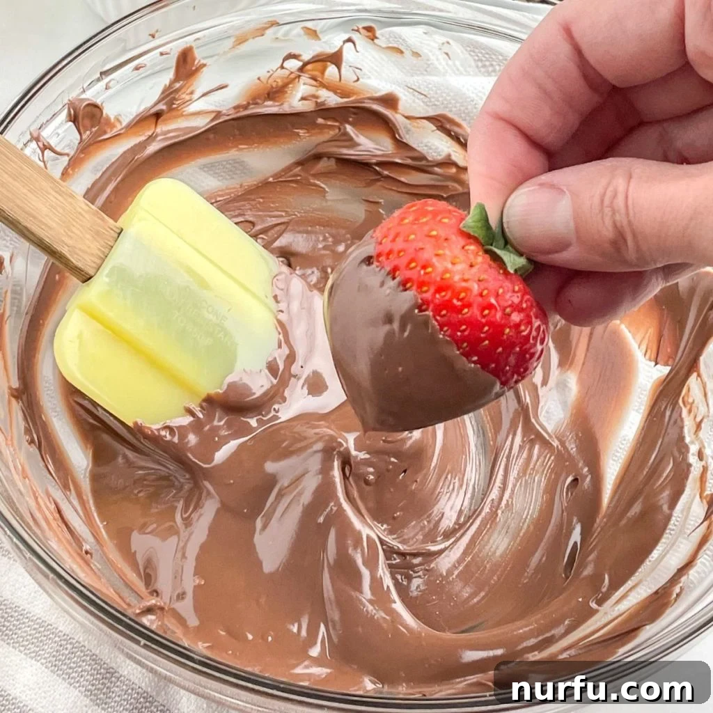Mastering Melted Chocolate: 3 Simple Techniques 2 Melted chocolate in a bowl with a strawberry.