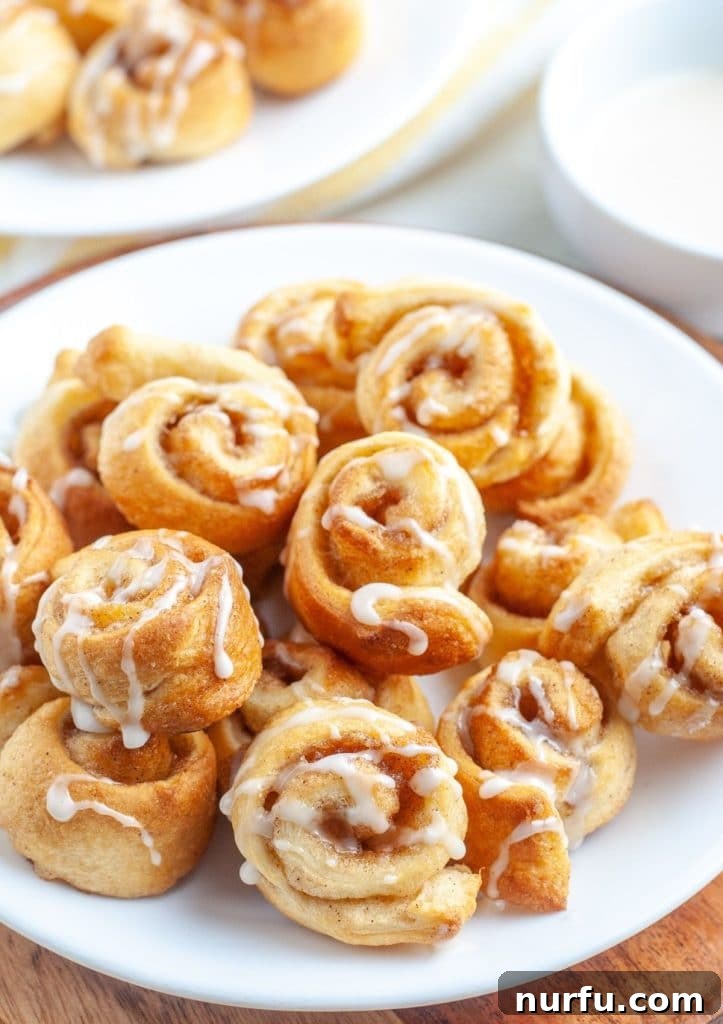 King's Cinnamon Crunch 2 Plate of golden-brown mini cinnamon rolls, drizzled with sweet white icing.