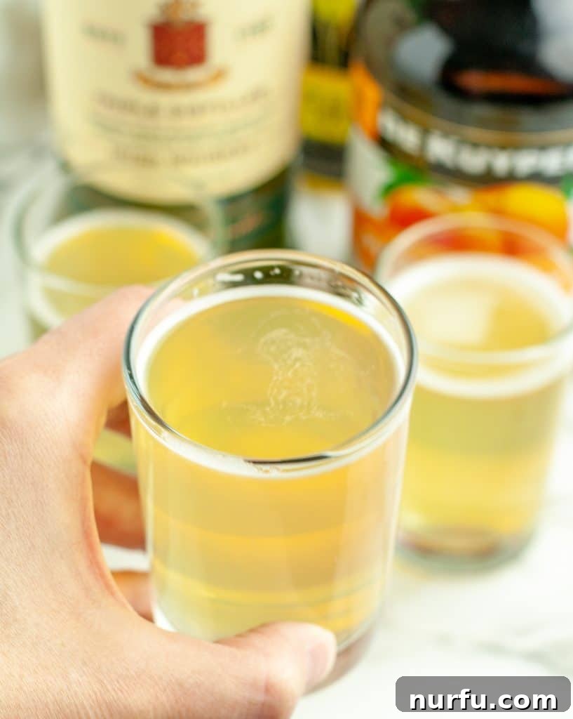 Your Guide to Green Tea Shots 4 A hand holding a shot glass filled with the vibrant green tea shot, ready for consumption.