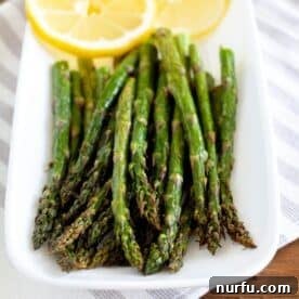 A plate featuring perfectly cooked asparagus spears, garnished with fresh lemon slices.