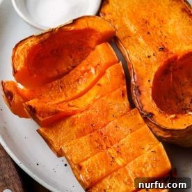 A beautifully roasted whole butternut squash presented on a plate, highlighting its golden exterior.
