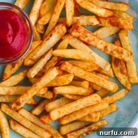 A generous plate of golden, homemade air fryer french fries, perfectly crispy and seasoned.