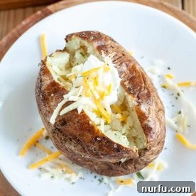 A perfectly baked potato topped with melted cheese and a dollop of sour cream.