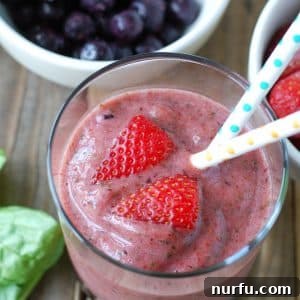 A glass of refreshing smoothie with strawberries and other fruits, presented as a delicious and healthy beverage.