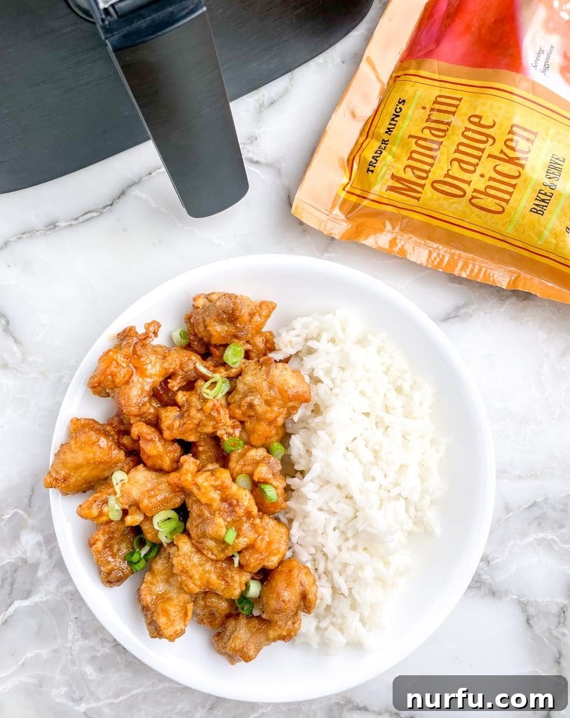 Crispy Trader Joes Orange Chicken Air Fryer 2 A bowl of crispy Trader Joe's Orange Chicken, garnished with green onions and sesame seeds, next to an air fryer.