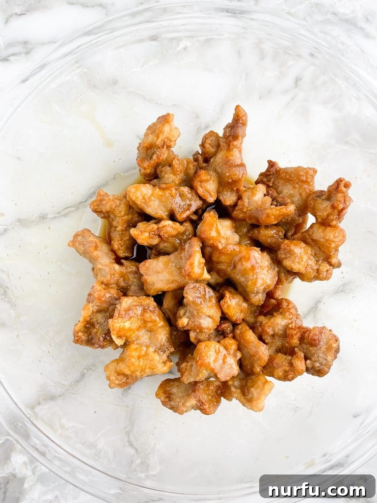 Crispy Trader Joes Orange Chicken Air Fryer 5 Crispy fried chicken pieces coated in a glistening orange sauce, ready to be served.