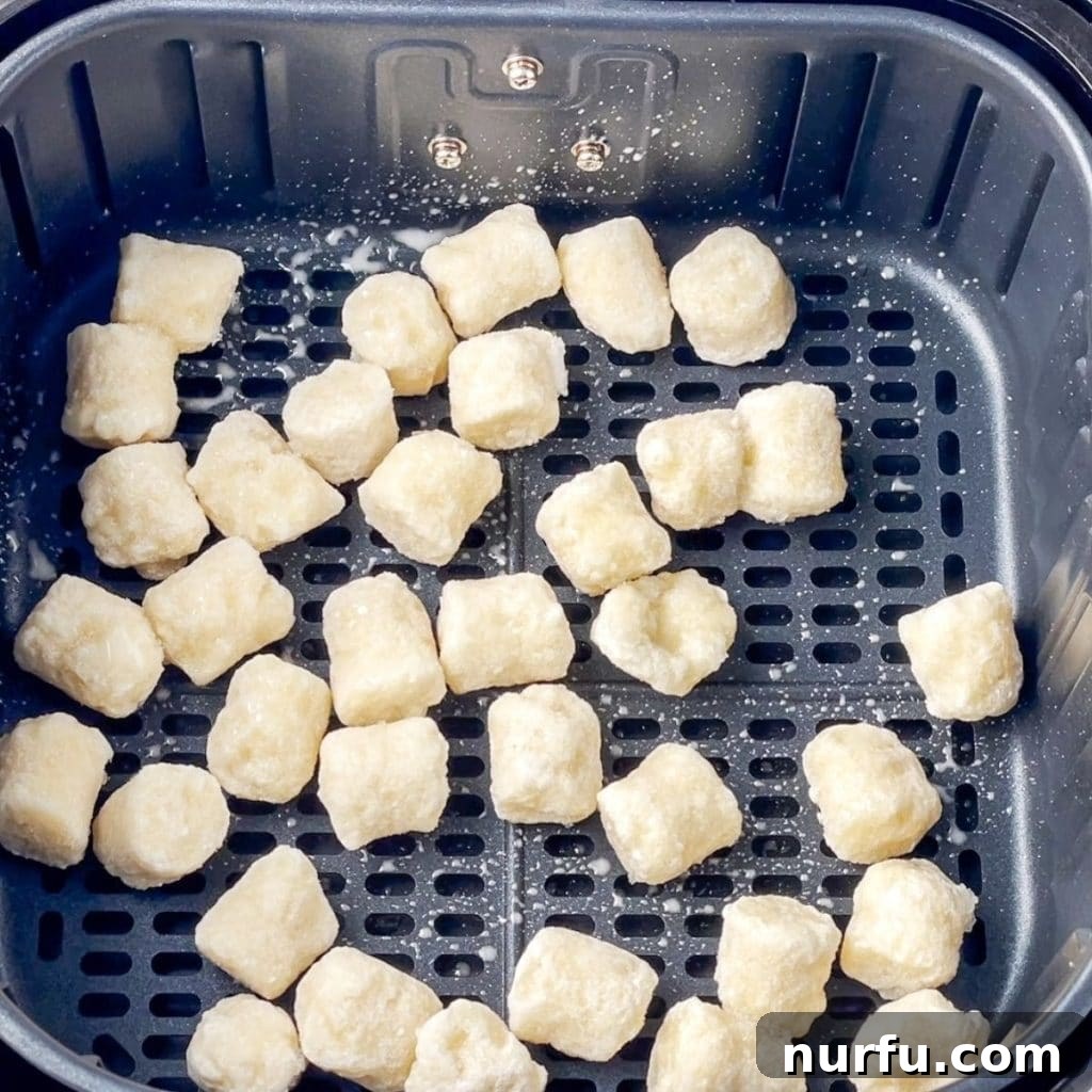 Crispy Air Fryer Cauliflower Gnocchi 4 Frozen cauliflower gnocchi evenly spread in a single layer in the air fryer basket before cooking.