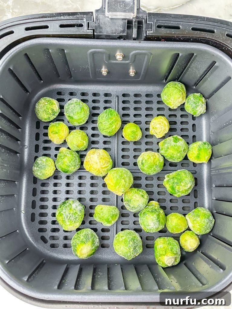 Crispy Air Fryer Frozen Brussels Sprouts Made Easy 4 Air fryer basket filled with a single layer of frozen brussels sprouts.