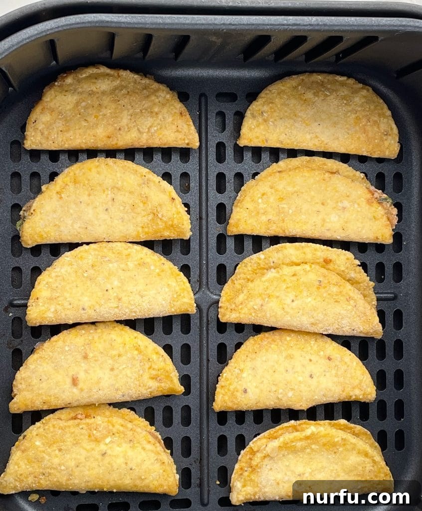 Perfect Air Fryer Frozen Mini Tacos Every Time 4 Frozen mini tacos neatly arranged in a single layer within an air fryer basket, ready for cooking.