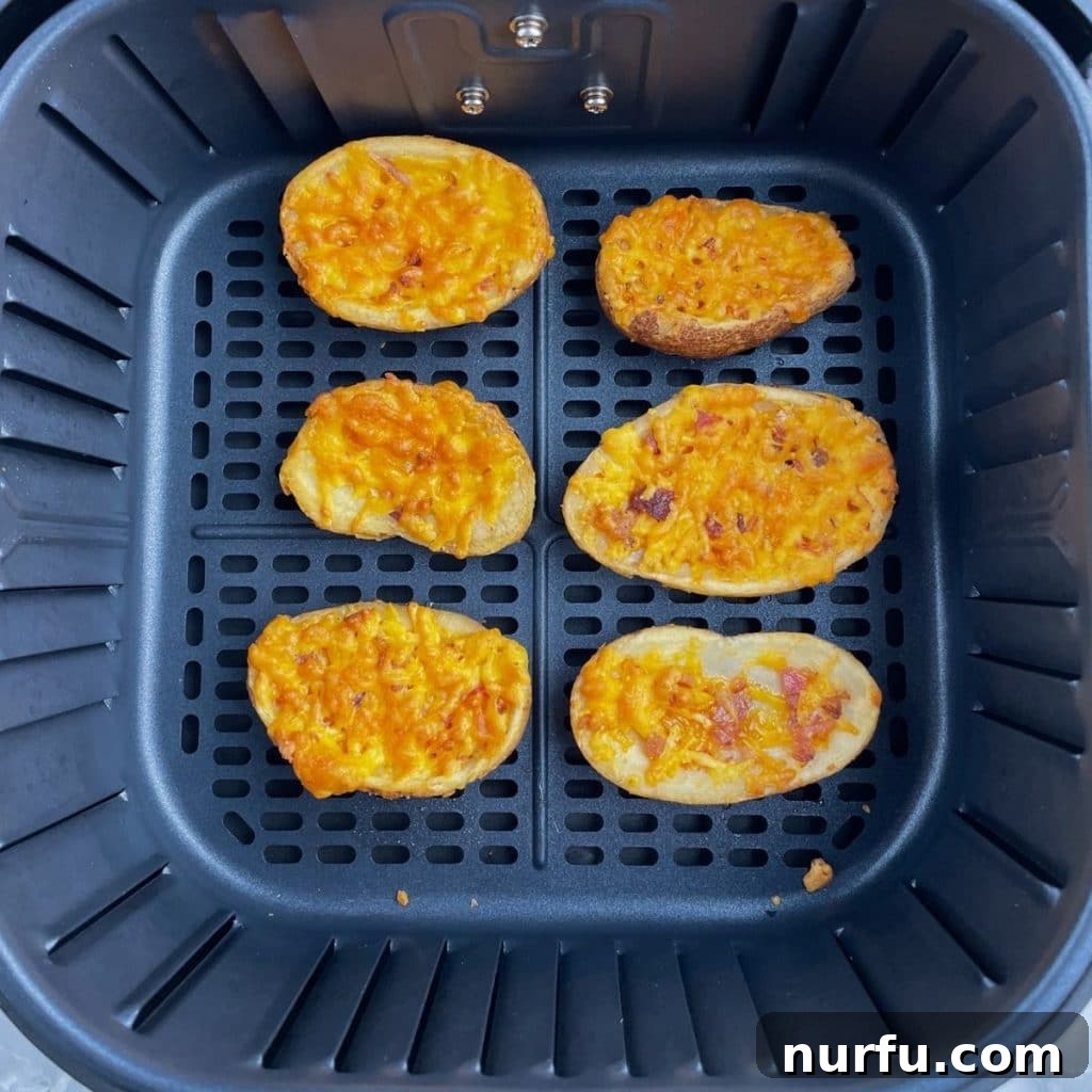 From Frozen to Fabulous: Air Fryer Potato Skins 5 A close-up view of freshly cooked potato skins, boasting a golden, crispy exterior and perfectly melted cheese, resting in an air fryer basket.