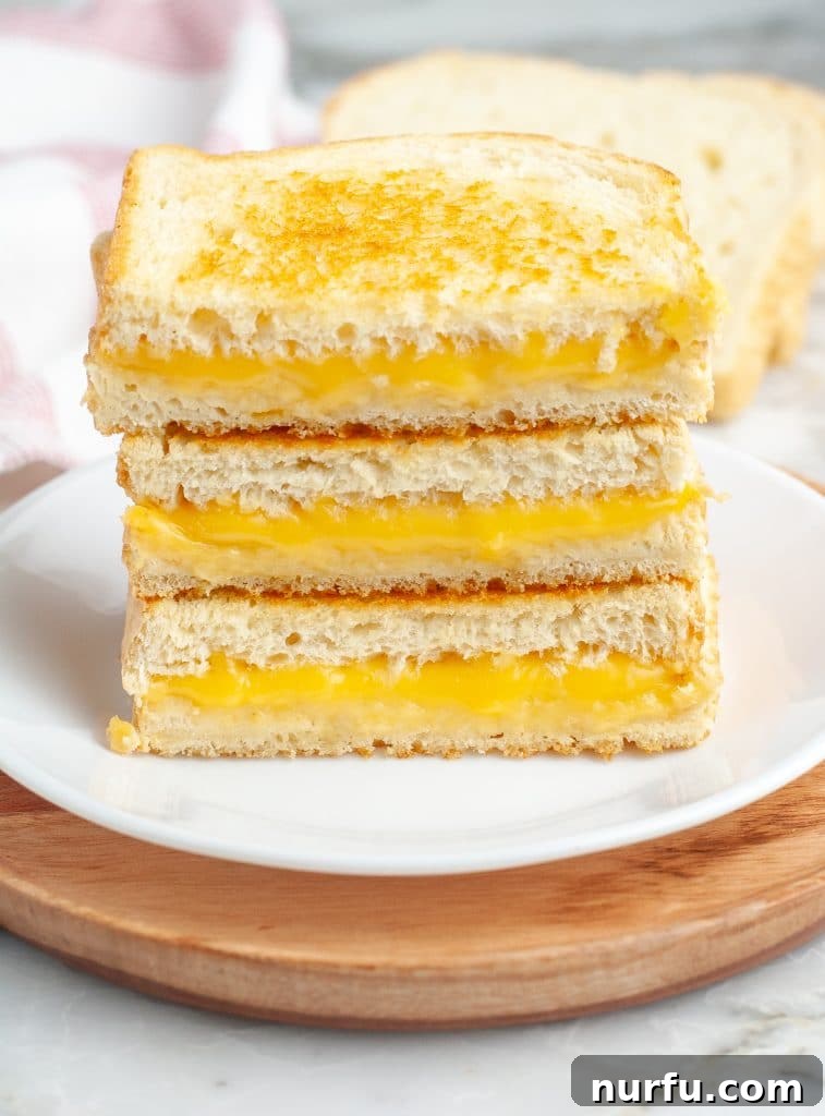 Stacked grilled cheese sandwiches on a plate, surrounded by various side dishes.