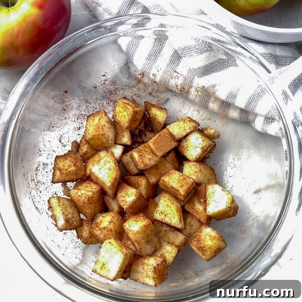 Diced apples with cinnamon in a bowl, ready for microwaving.