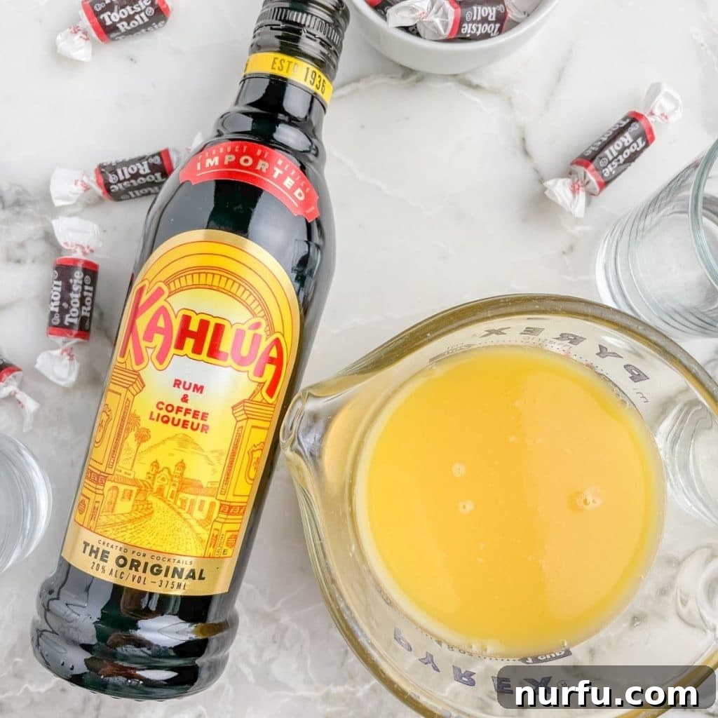 Bottle of Kahlua and a glass of orange juice, the two key ingredients for a Tootsie Roll Shot.