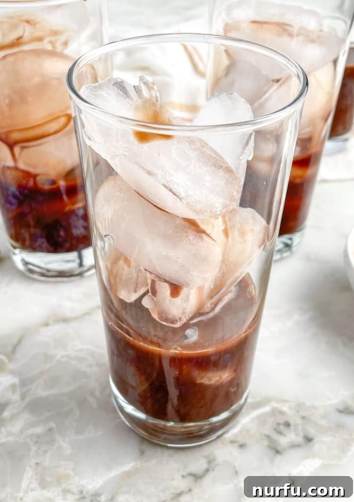 Velvet Chocolate Cream Soda 4 A glass filled with ice and rich, dark chocolate simple syrup, ready for the next steps of the cream soda.