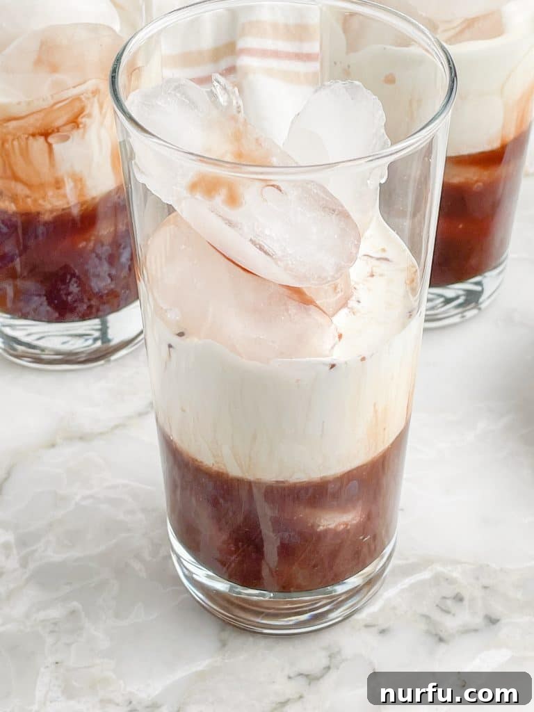 Velvet Chocolate Cream Soda 5 A glass partially filled with chocolate syrup and a layer of creamy half and half, showcasing the preparation of the Italian cream soda.
