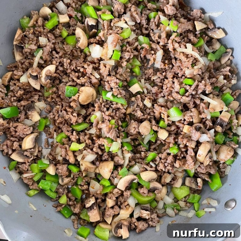 Ultimate Easy Pizza Bowl 4 Skillet filled with browned ground sausage, vibrant green bell peppers, and diced onions, ready for the next step of assembly.