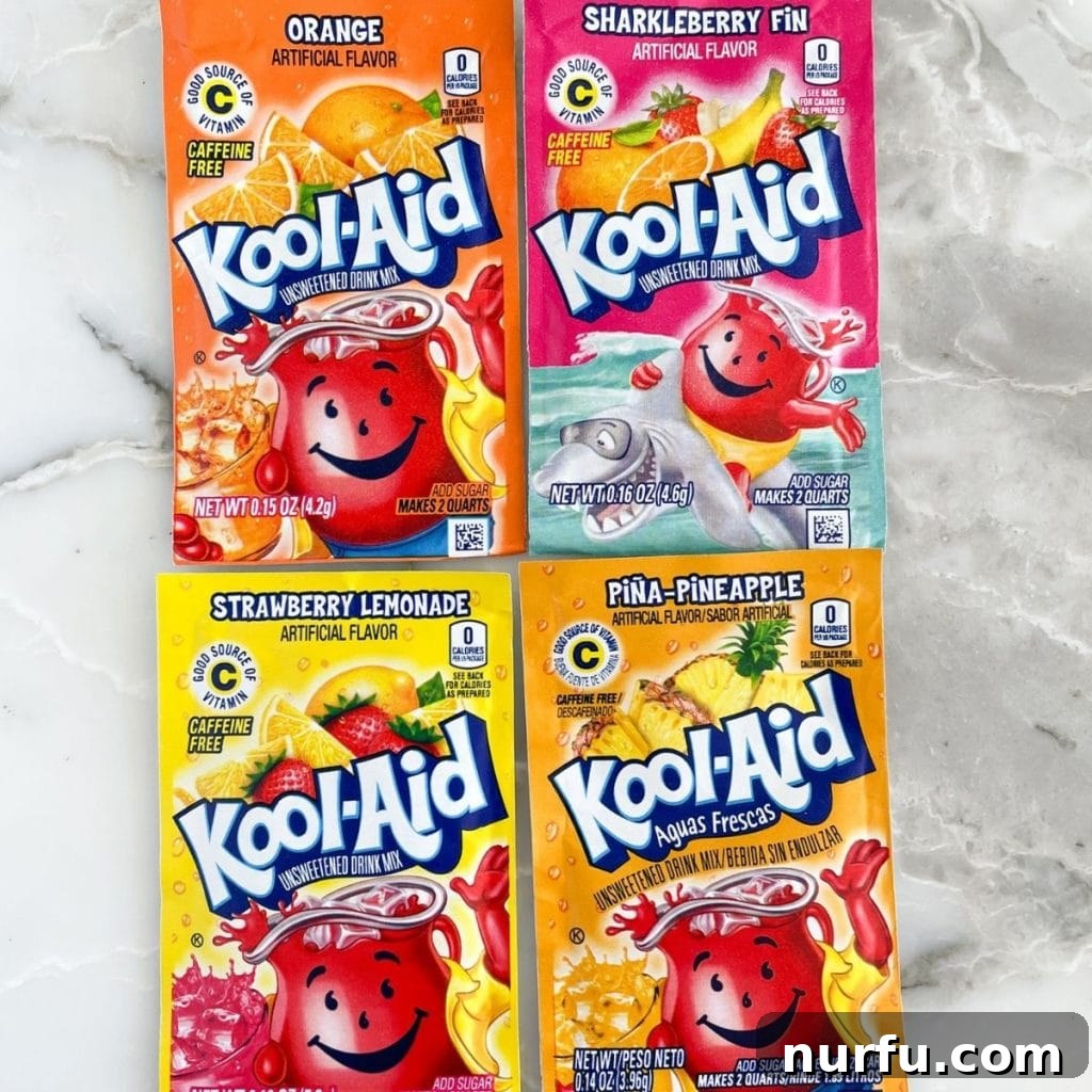 A selection of Kool-Aid Jammers and powder packets, featuring Orange, Sharkleberry Fin, Strawberry Lemonade, and Aguas Frescas Piña Pineapple.