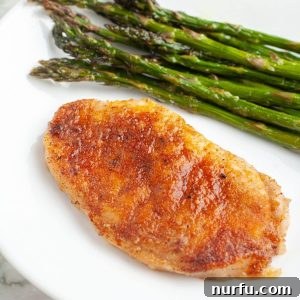A perfectly cooked pork chop on a plate, served with fresh asparagus, highlighting its tenderness.