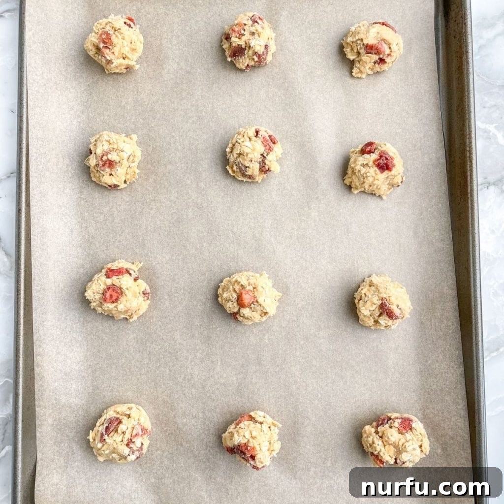 Strawberry Oat Delight Cookies 5 Rows of scooped cookie dough balls arranged neatly on a parchment-lined baking sheet, ready for baking.