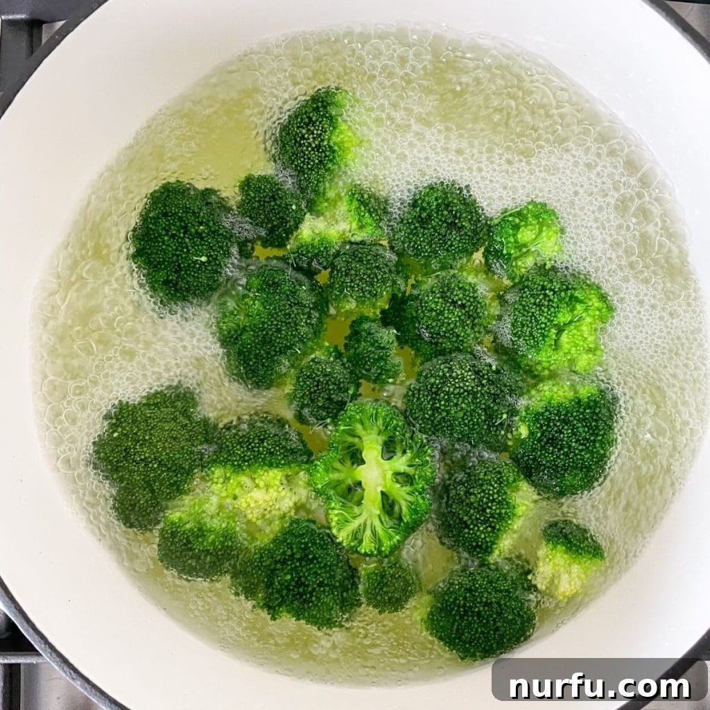 Achieve Perfectly Boiled Broccoli 4 Close-up shot of bright green broccoli florets immersed in a pot of vigorously boiling, salted water, capturing the cooking process in action.