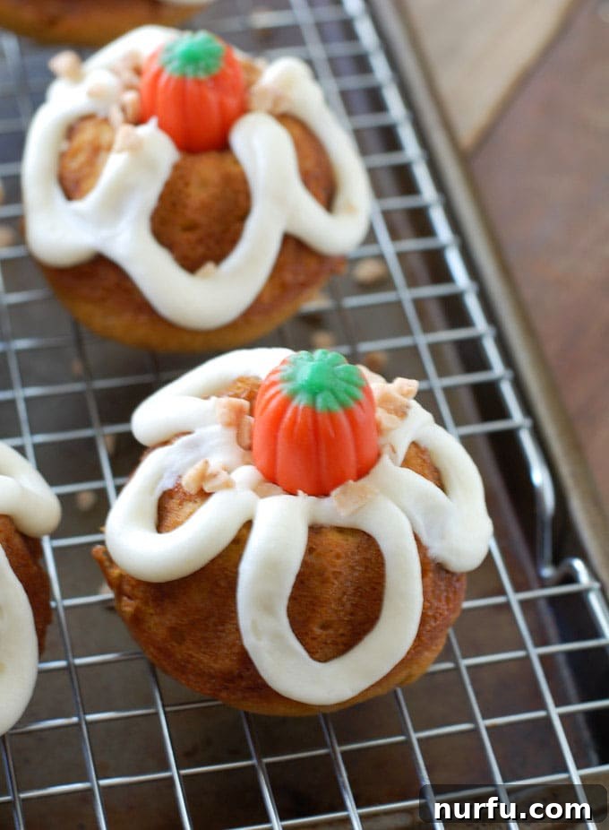 A close-up of a beautifully frosted toffee bundt cake, topped with extra toffee and a small candy pumpkin, highlighting its delicious details.