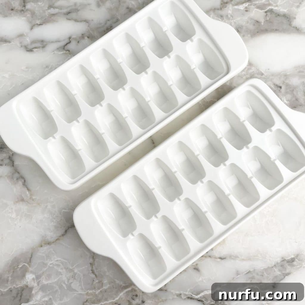 Water's Freezing Journey Uncovered 3 Two white ice cube trays, one filled with water, ready for the freezer.