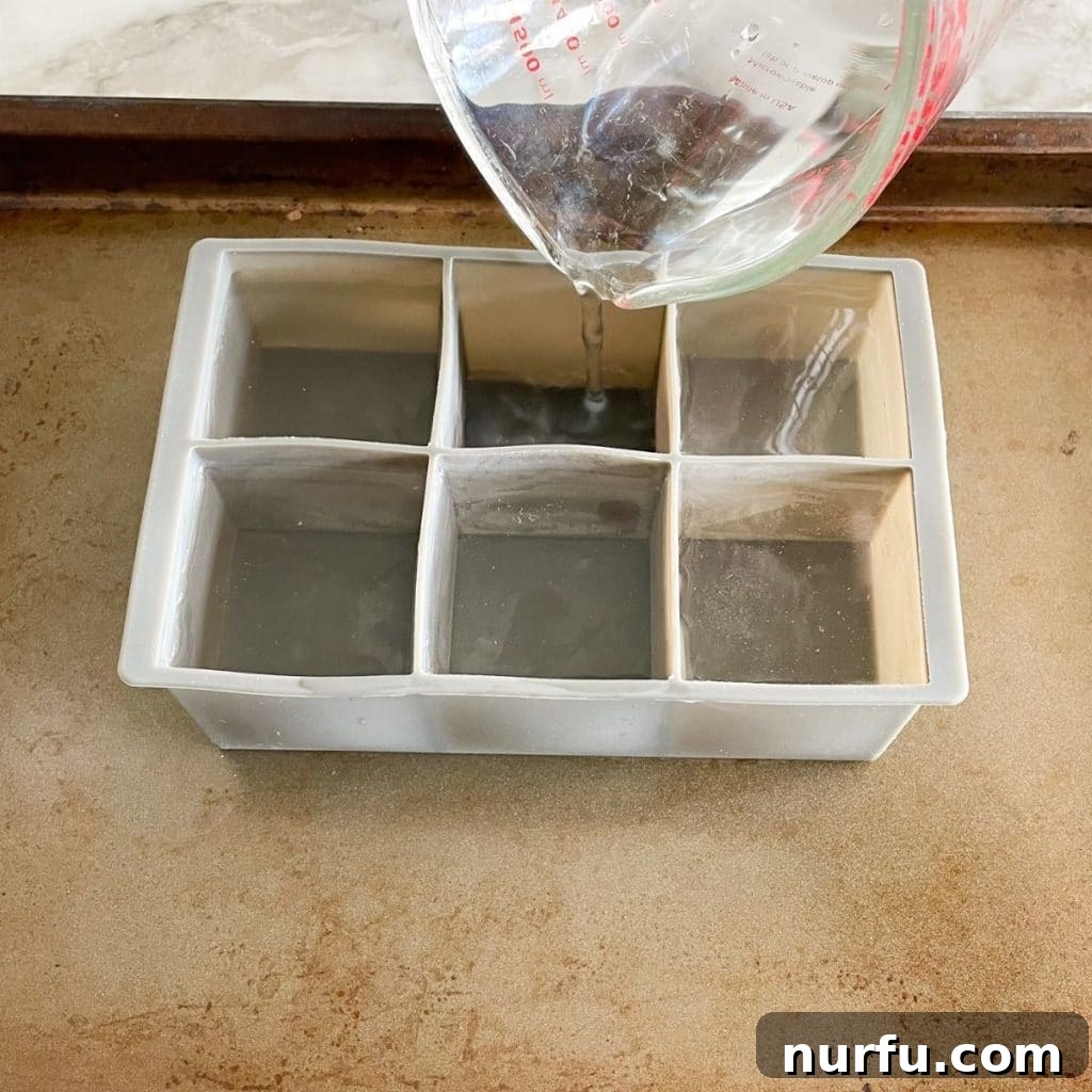 Water's Freezing Journey Uncovered 4 Water being poured into an empty ice cube tray, illustrating the preparation for freezing.