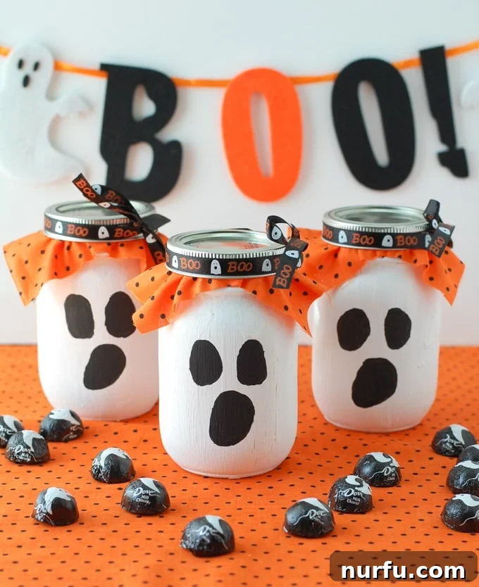 Collection of Ghost Mason Jar Gifts Three completed ghost mason jars, filled with candy and decorated, arranged attractively.