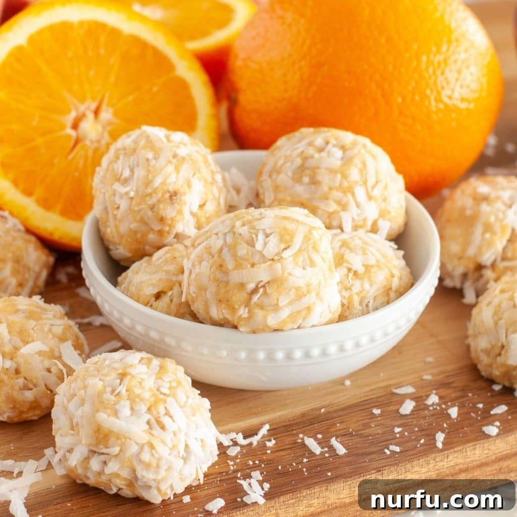 Zesty Orange Coconut Delights 2 A beautifully arranged bowl of orange coconut balls, garnished with fresh orange slices, radiating a vibrant and inviting appeal.