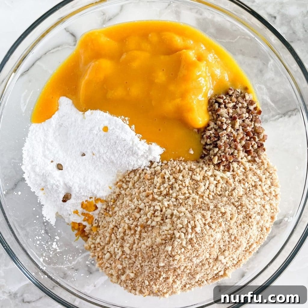 Zesty Orange Coconut Delights 4 A bowl containing a vibrant orange mixture of cookie crumbs, powdered sugar, pecans, and orange juice concentrate, being stirred during the preparation process.