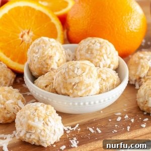 Zesty Orange Coconut Delights 6 Orange Coconut Balls, beautifully arranged in a bowl with fresh orange slices, ready to be enjoyed.