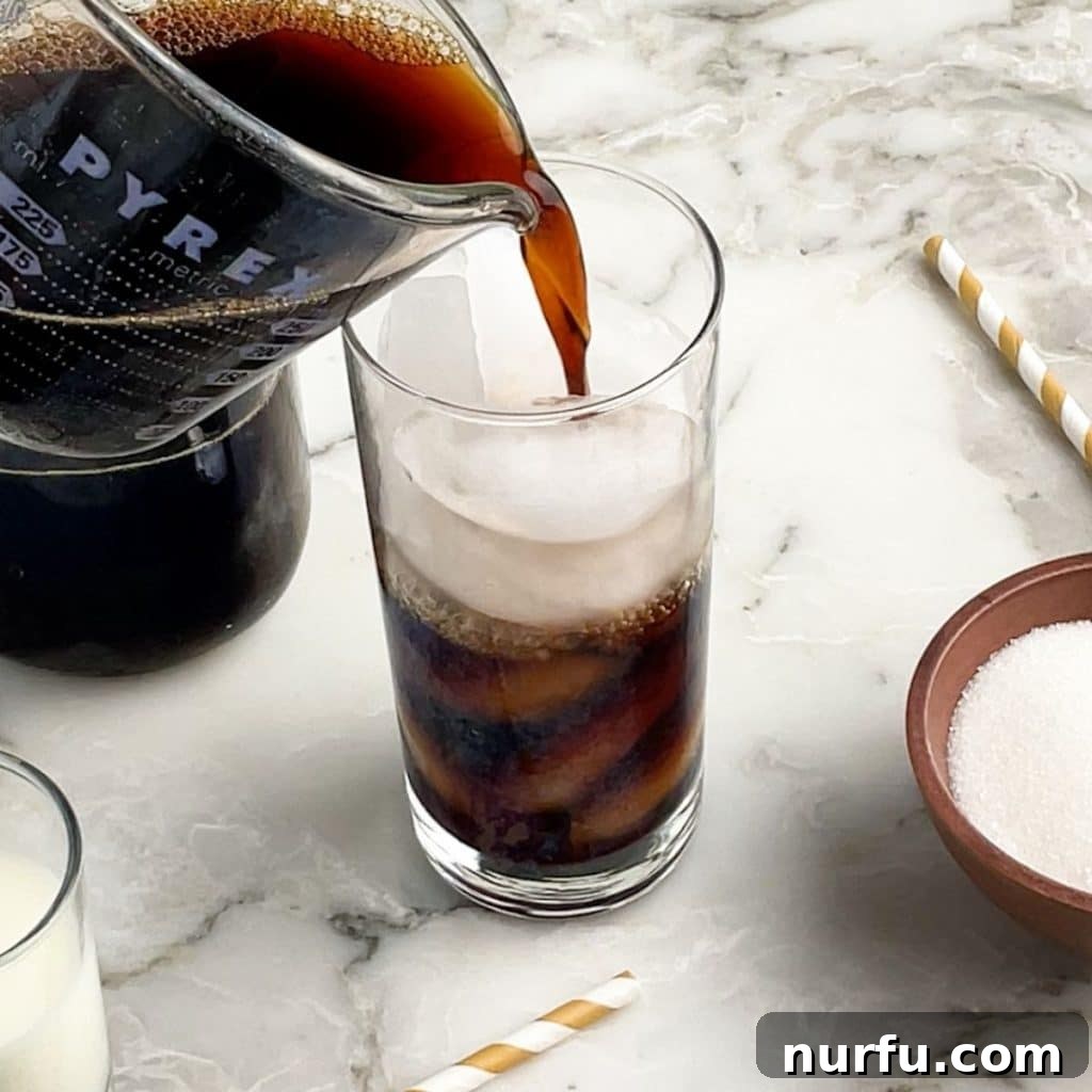 Crafting Perfect Iced Coffee at Home 3 Chilled coffee being poured into a tall glass filled with ice, preparing for the next step in making iced coffee.