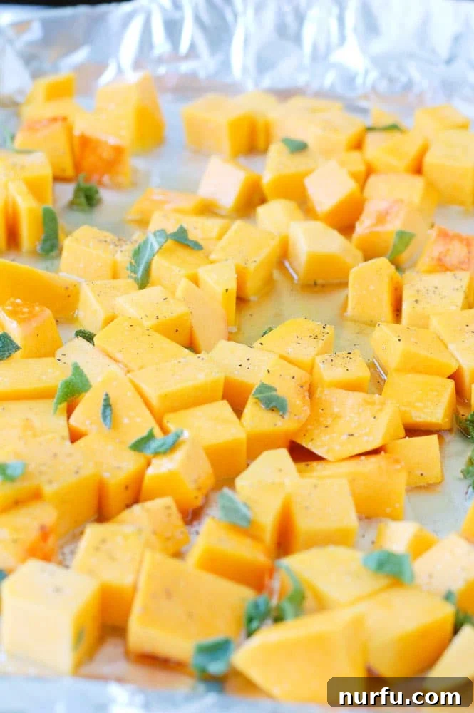 Close-up shot of roasted butternut squash cubes with flecks of fresh sage, showcasing the beautiful golden-brown caramelization.