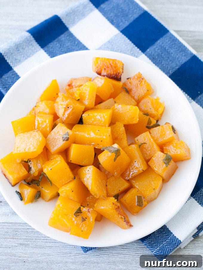 A baking sheet filled with maple sage butternut squash cubes, freshly roasted and glistening, ready to be served.