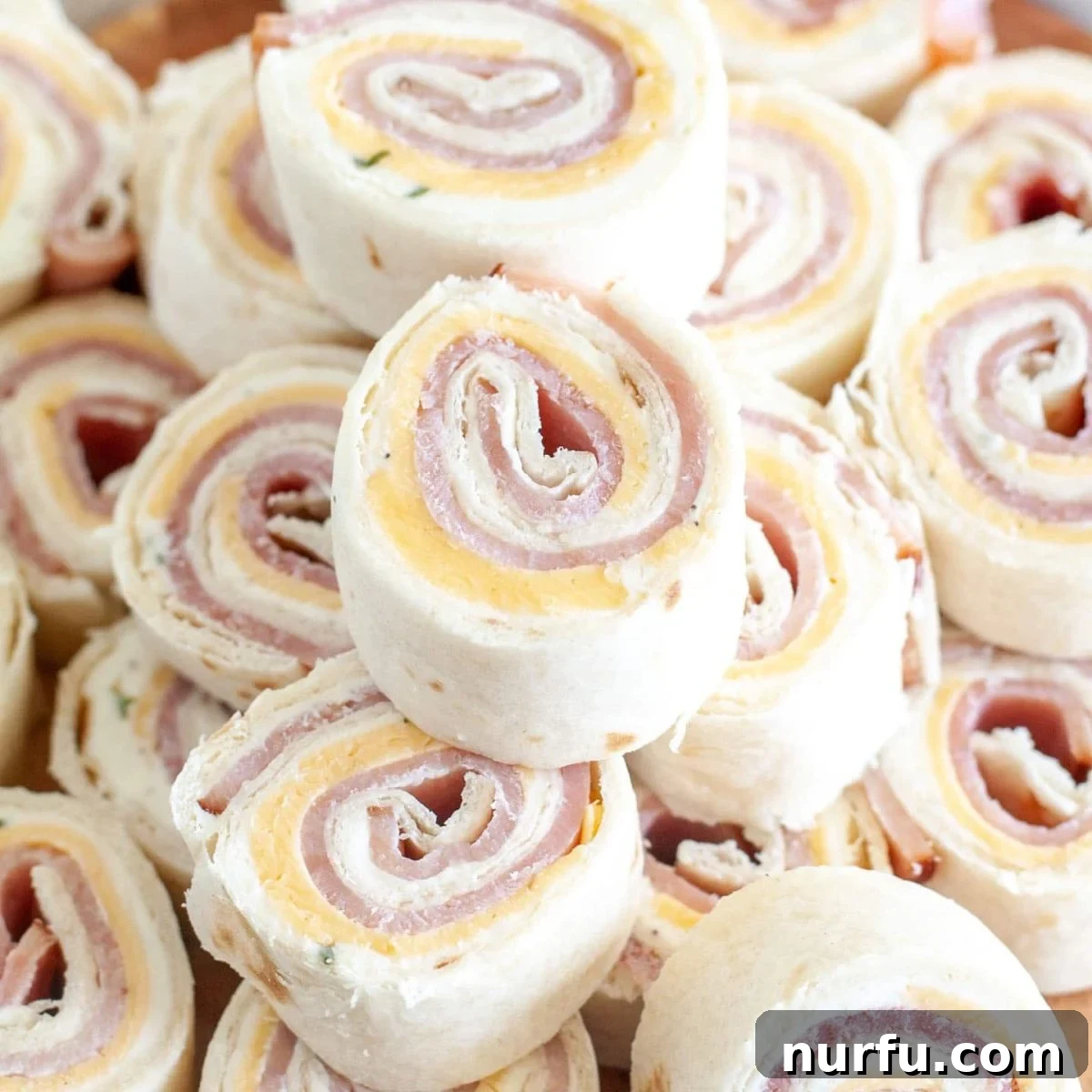 50 Refreshing Cold Lunch Ideas 3 Delicious ham and cheese roll-ups stacked on a plate, perfect for a fun and easy cold lunch or appetizer.