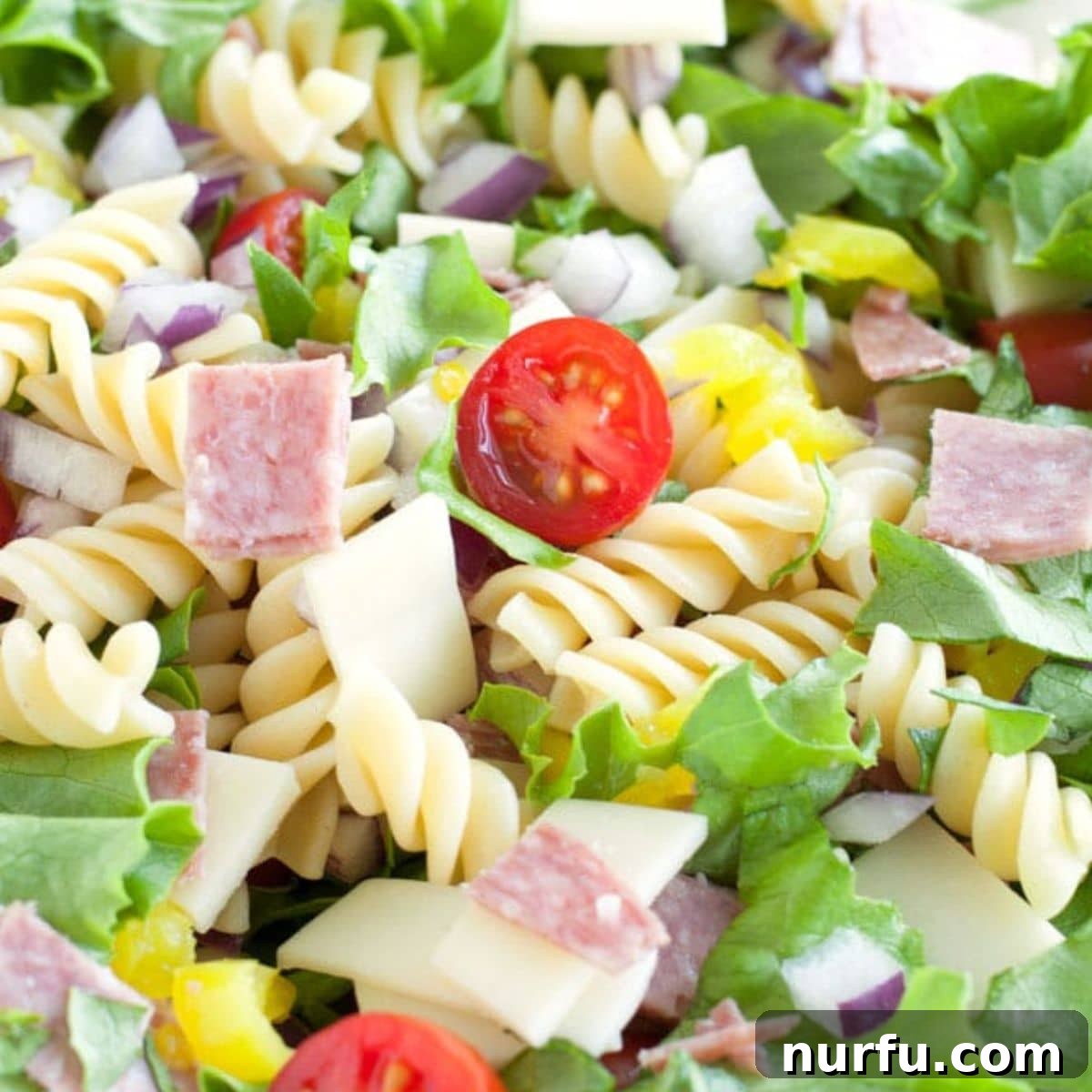 50 Refreshing Cold Lunch Ideas 7 A colorful bowl of Italian sub pasta salad, featuring pasta mixed with salami, provolone, and fresh vegetables in a vinaigrette.