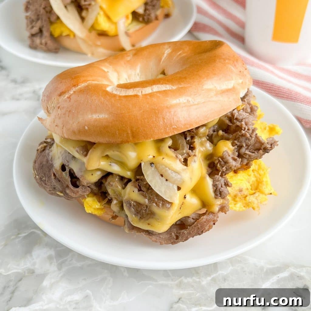 Homemade McDonald's Steak Egg And Cheese Bagel 2 A perfectly assembled homemade Steak, Egg, and Cheese Bagel sandwich on a rustic plate, ready to be enjoyed.
