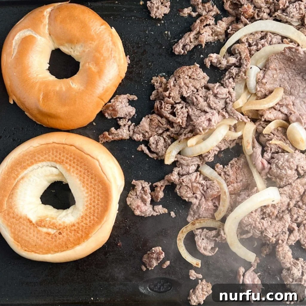 Homemade McDonald's Steak Egg And Cheese Bagel 7 Shaved steak and cooked onions mingling on a griddle, topped with melting slices of American cheese, forming individual portions.