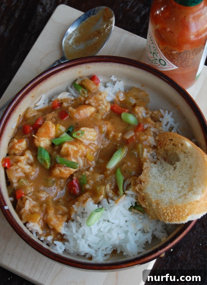 Authentic Shrimp Etouffee A steaming bowl of homemade Shrimp Etouffee, served with white rice and a side of crusty bread, garnished with fresh parsley.