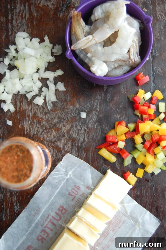 Fresh Ingredients for Shrimp Etouffee Fresh, raw shrimp, alongside a block of butter, and finely diced red and yellow bell peppers and onions, ready for cooking.
