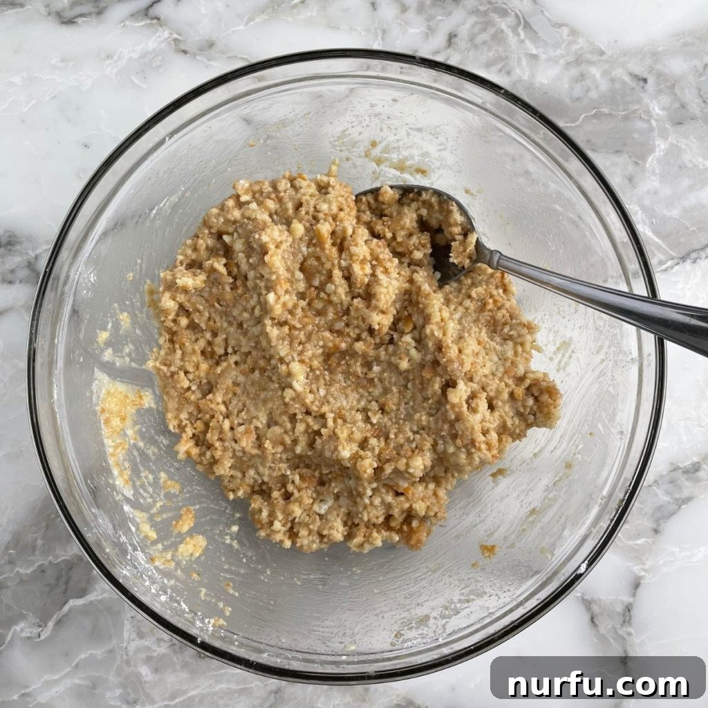Zesty Coconut Lime Bites 4 A large mixing bowl filled with finely crushed cookie crumbs, with a spoon resting inside, ready for the next ingredients to be added.