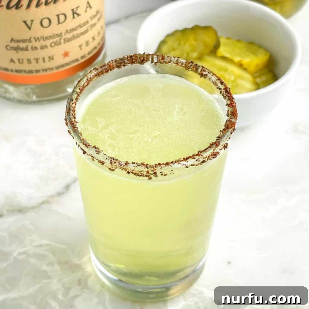 Shot glass with green liquid and bowl of pickles, ready to be enjoyed.
